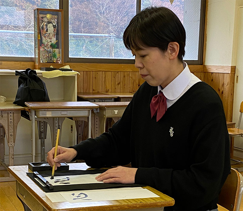 A Kimino High School senior teaching how to use a paintbrush