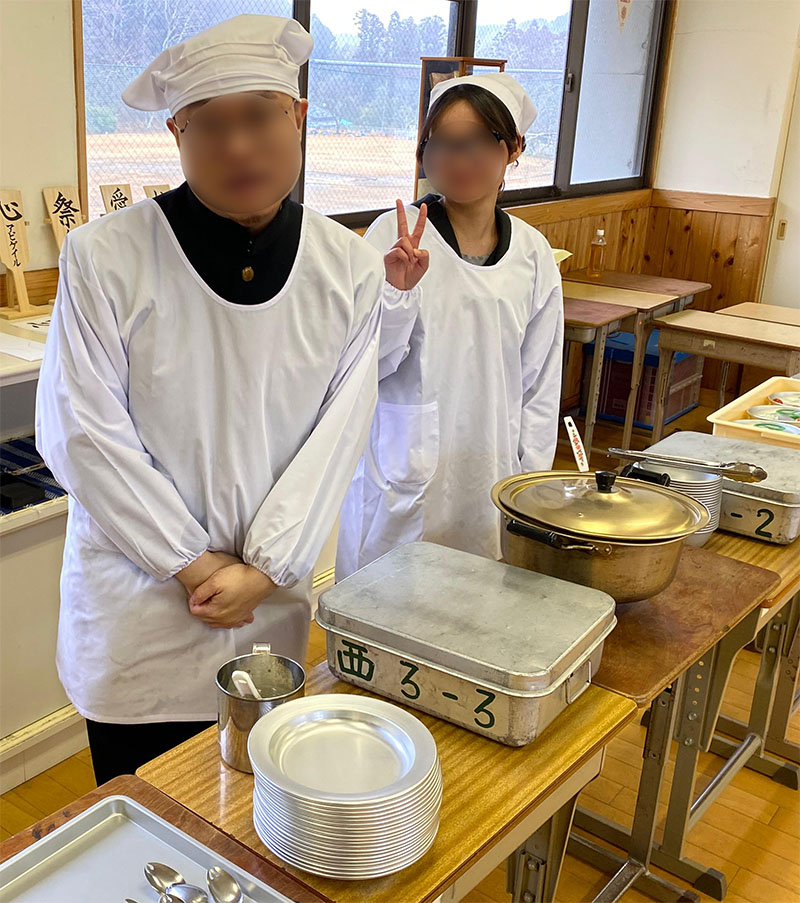 Two students dressed in white ready to serve lunch